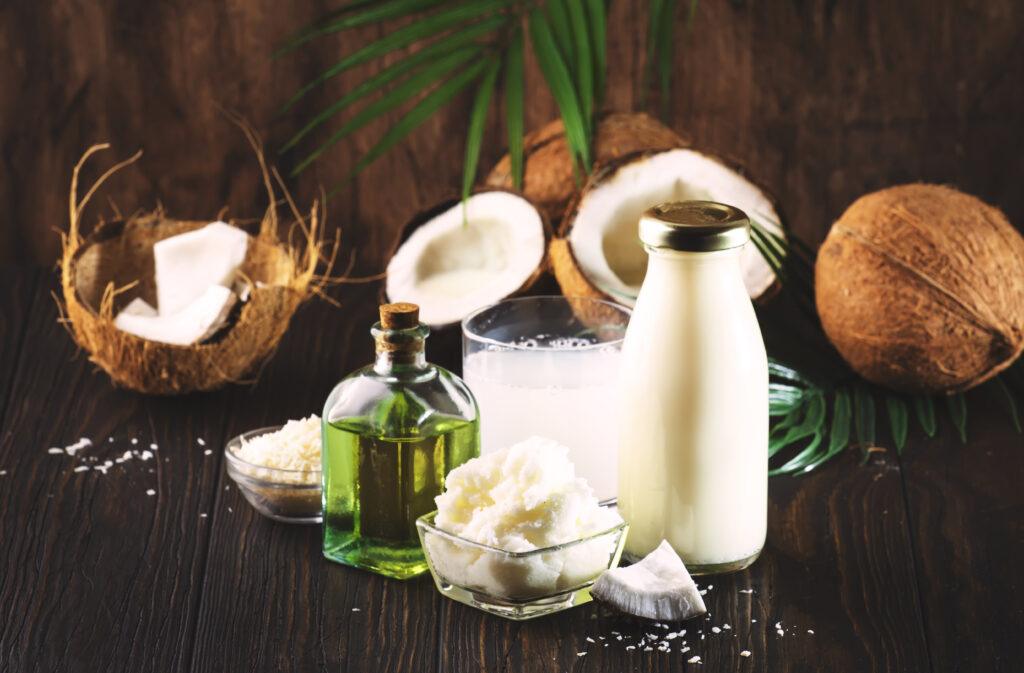 Coconuts products - mct butter, oil, milk, shavings on wooden table background. Hair, skin and body treatment and healthy food concept