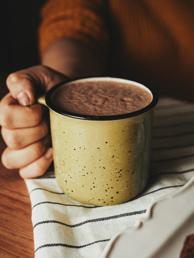 girl holds out a mug of hot cocoa in her hand